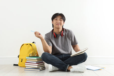 Student with notebook and pen studying on floor indoorsの写真素材