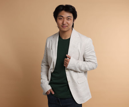 Portrait of handsome Asian businessman in suit on beige background