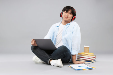 Student with headphones and laptop on grey backgroundの写真素材