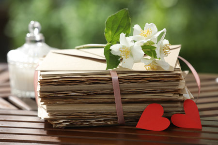 Stack of love letters, paper hearts and flowers on wooden table, closeupの写真素材