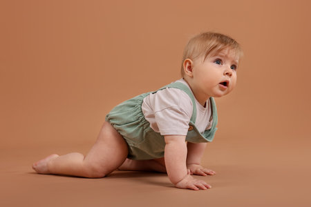 Cute little baby crawling on pale brown backgroundの写真素材