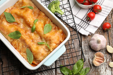 Tasty vegetarian lasagna in baking dish and ingredients on wooden table, flat layの写真素材