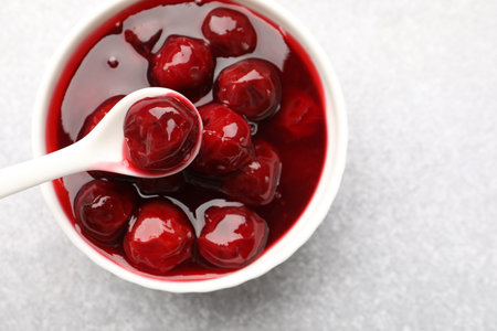Tasty cherry jam on light table, top view