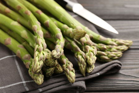Fresh raw asparagus and knife on black wooden table, closeupの写真素材