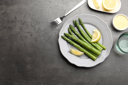 Tasty cooked asparagus served with lemon on gray table, flat lay. Space for textの写真素材