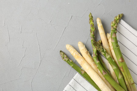 Different raw asparagus spears on gray table, top view. Space for textの写真素材
