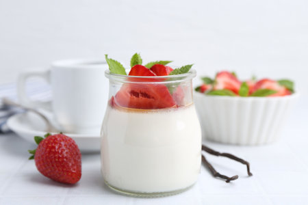 Tasty panna cotta with caramel, strawberries, mint and vanilla pods on white table, closeupの写真素材