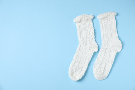 Pair of comfortable white socks on light blue background, top view. Space for textの写真素材