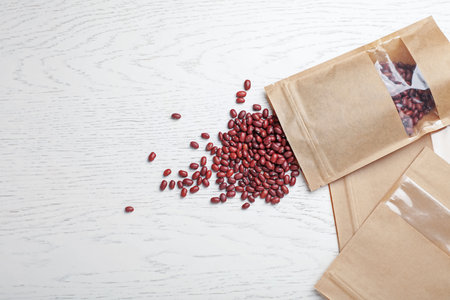 Zipper stand-up pouches and dry kidney beans on white wooden table, flat lay. Mockup for designの写真素材