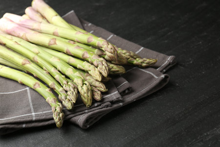 Fresh raw asparagus spears on black table, closeup. Space for textの写真素材