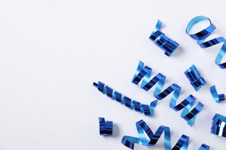 Shiny serpentine streamers on white background, flat lay. Space for textの写真素材