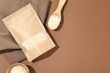 Zipper stand-up pouch and white rice on brown background, flat lay. Mockup for designの写真素材