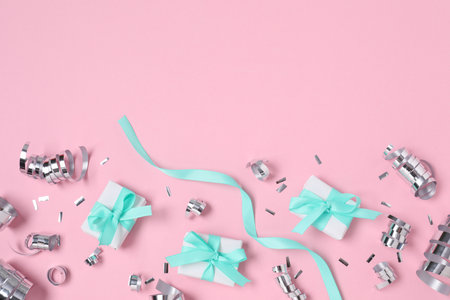Shiny party streamers, confetti and gifts on pink background, flat lay. Space for textの写真素材