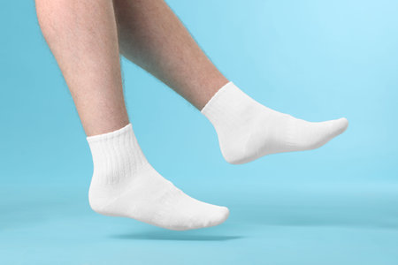 Man wearing clean white socks on light blue background, closeup