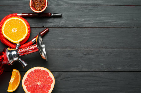Hookah and fresh fruits on black wooden table, flat lay. Space for text