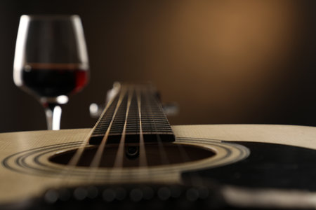 Acoustic guitar and glass of red wine on black background, closeup. Space for textの写真素材