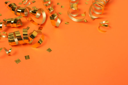 Shiny party streamers and confetti on orange background, closeup. Space for textの写真素材
