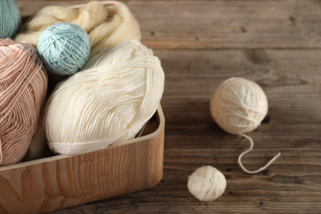 Felting wool and knitting yarn on wooden table, closeup