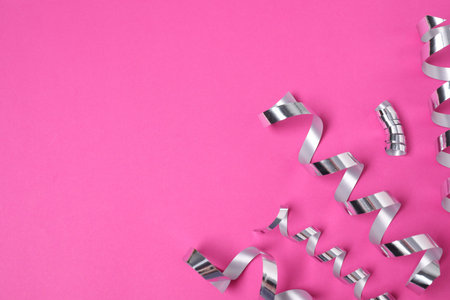 Shiny party streamers on pink background, flat lay. Space for textの写真素材