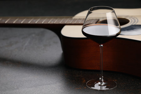 Acoustic guitar and red wine on black table, closeupの写真素材