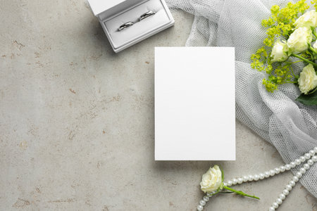 Wedding invitation card, silver rings and flowers on gray textured table, flat lay. Space for textの写真素材