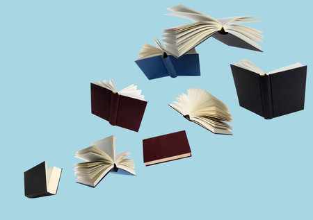 Hardcover books flying like birds against light blue backgroundの写真素材