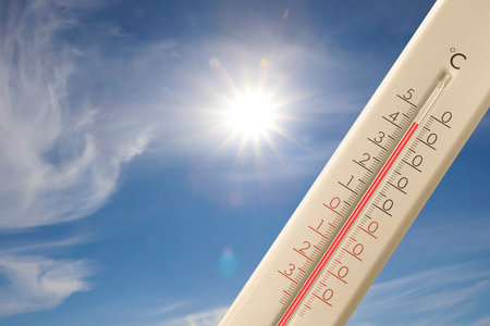 Extremely high temperature on thermometer against blue sky on sunny day. Summer weatherの写真素材