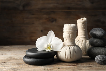 Herbal bags, spa stones and orchid flower on wooden table. Space for textの写真素材