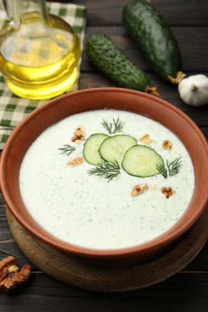Tasty cucumber soup with dill, walnuts and ingredients on wooden table, closeupの写真素材