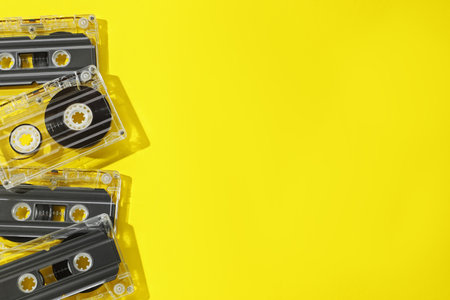 Audio cassettes with magnetic tapes on yellow background, flat lay. Space for textの写真素材