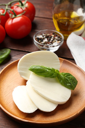 Tasty mozzarella, tomatoes and basil on wooden table, closeupの写真素材