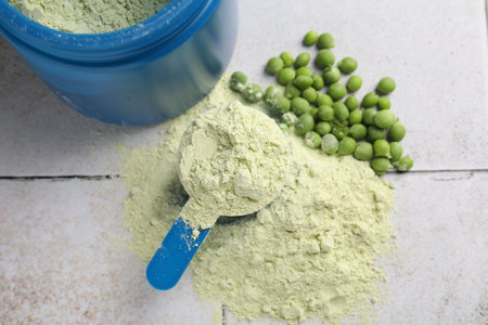 Protein powder and green peas on light tiled table, flat layの写真素材
