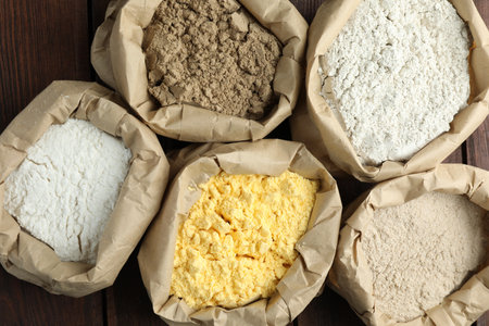 Different types of flour in paper bags on wooden table, flat layの写真素材