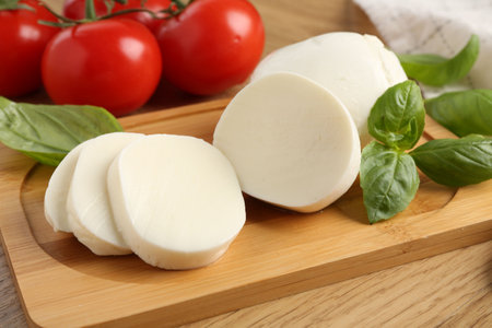 Tasty mozzarella, tomatoes and basil on wooden table, closeupの写真素材