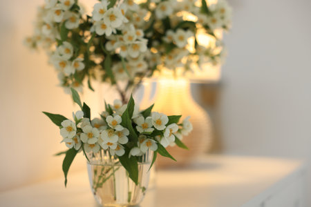Bouquet of beautiful jasmine flowers in vase on white table indoors, closeup. Space for textの写真素材