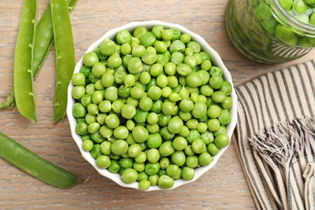 Fresh green peas in bowl, jar and pods on wooden table, flat lay. Pickling vegetablesの写真素材