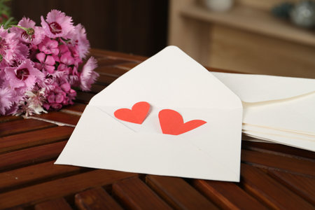 Love letters, red hearts and flowers on wooden table indoors, closeup