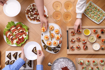 Buffet menu. People taking tasty appetizers from wooden table, top viewの写真素材
