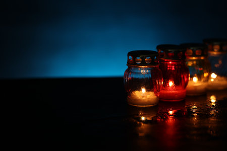Many grave candles on black table against blue background, closeup. Space for textの写真素材