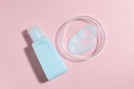Cosmetic product in Petri dish and bottle on pink background, flat layの写真素材