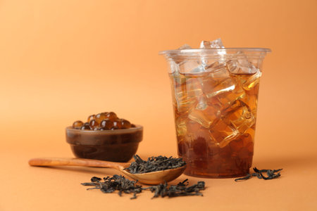 Tasty iced bubble tea and ingredients on orange backgroundの写真素材