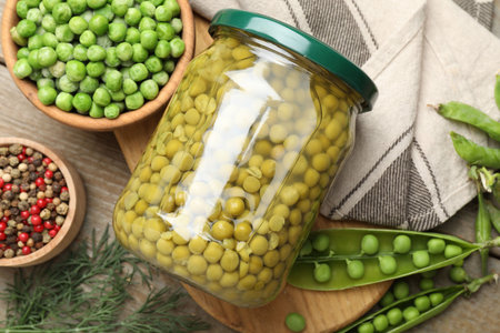 Pickled peas in jar, spices, dill and pods on wooden table, flat layの写真素材