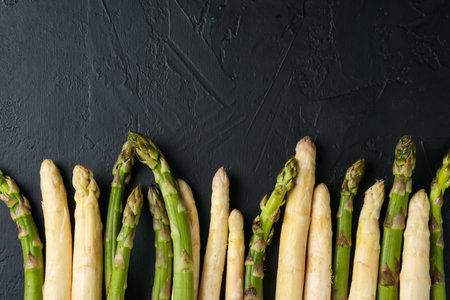 Green and white asparagus on black table, flat lay. Space for textの写真素材