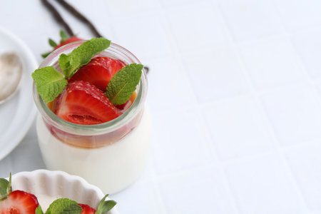 Tasty panna cotta with caramel, strawberries, mint and vanilla pods on white table, closeup. Space for textの写真素材