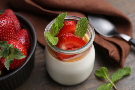 Tasty panna cotta with caramel, strawberries and mint on wooden table, closeupの写真素材