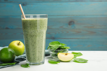Tasty spinach smoothie and ingredients on white marble table, closeup. Space for textの写真素材