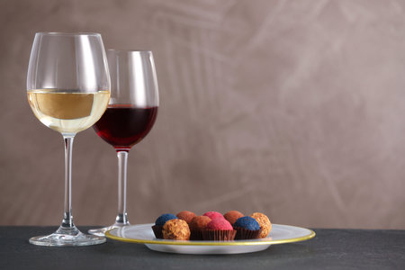 Delicious truffle bonbons and wine on black table against gray background. Space for textの写真素材