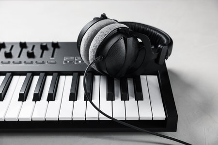 MIDI keyboard with headphones on white table, closeupの写真素材