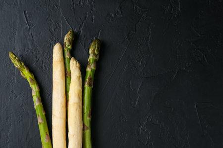 Green and white asparagus on black table, flat lay. Space for textの写真素材