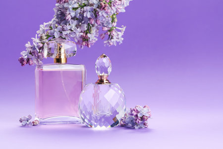 Bottles with perfumes and lilac flowers on purple gradient background, closeup. Space for text